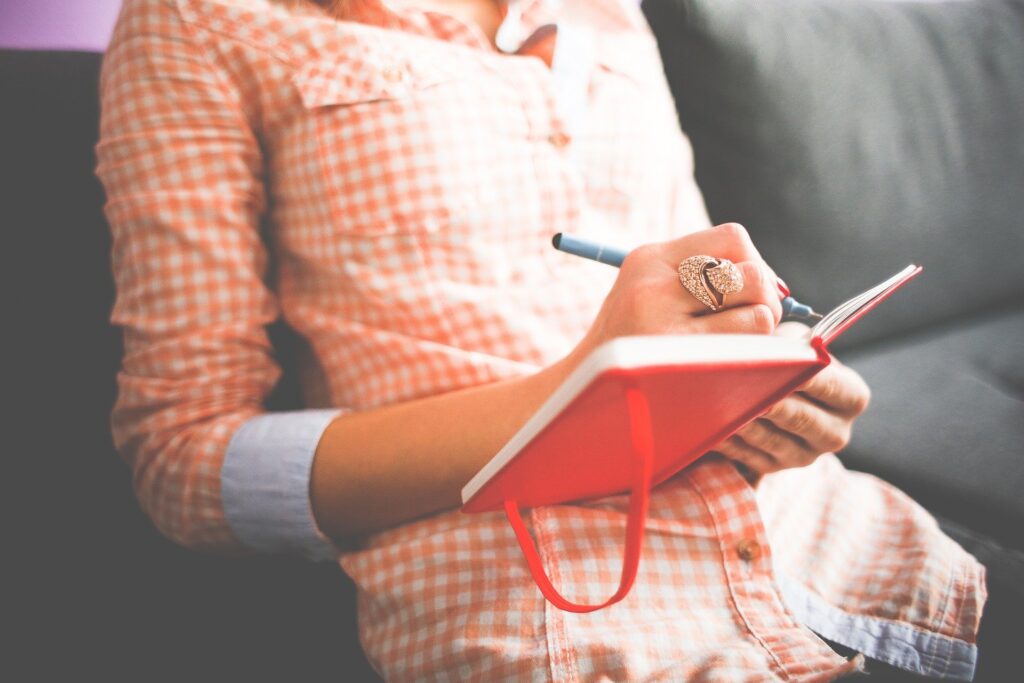 woman in orange plaid shirt writing in journal