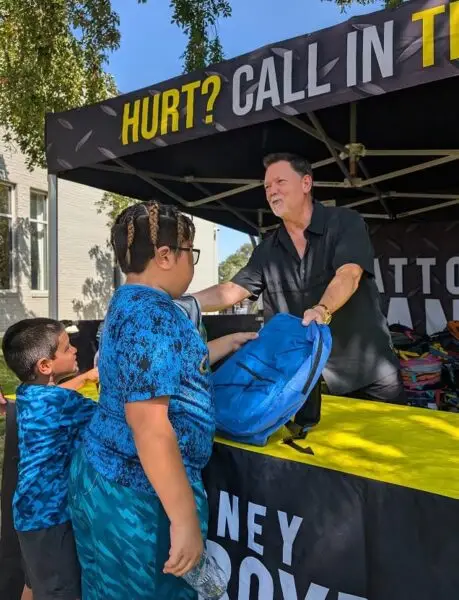 Attorney Dean Boyd handing out backpacks to children at a local community event.